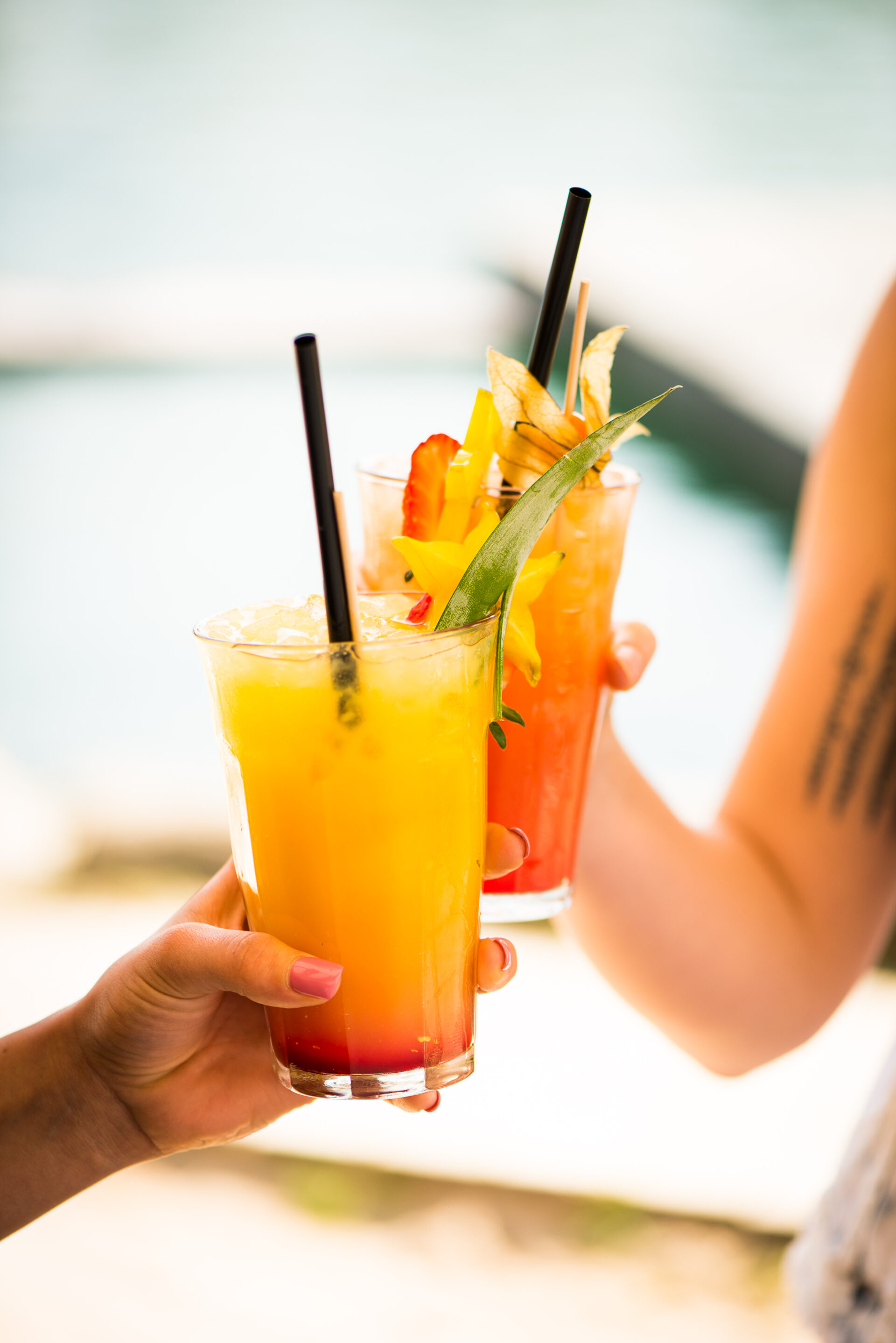 Nahaufnahme von zwei Händen, die jeweils mit Cocktails anstoßen