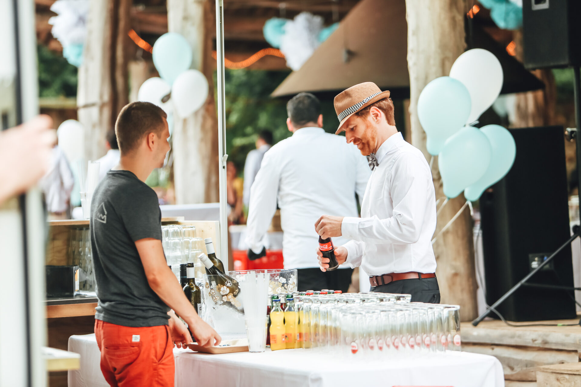 Outdoor Getränkestation bei einer Hochzeit. Ein Mann öffnet eine Cola-Glasflasche