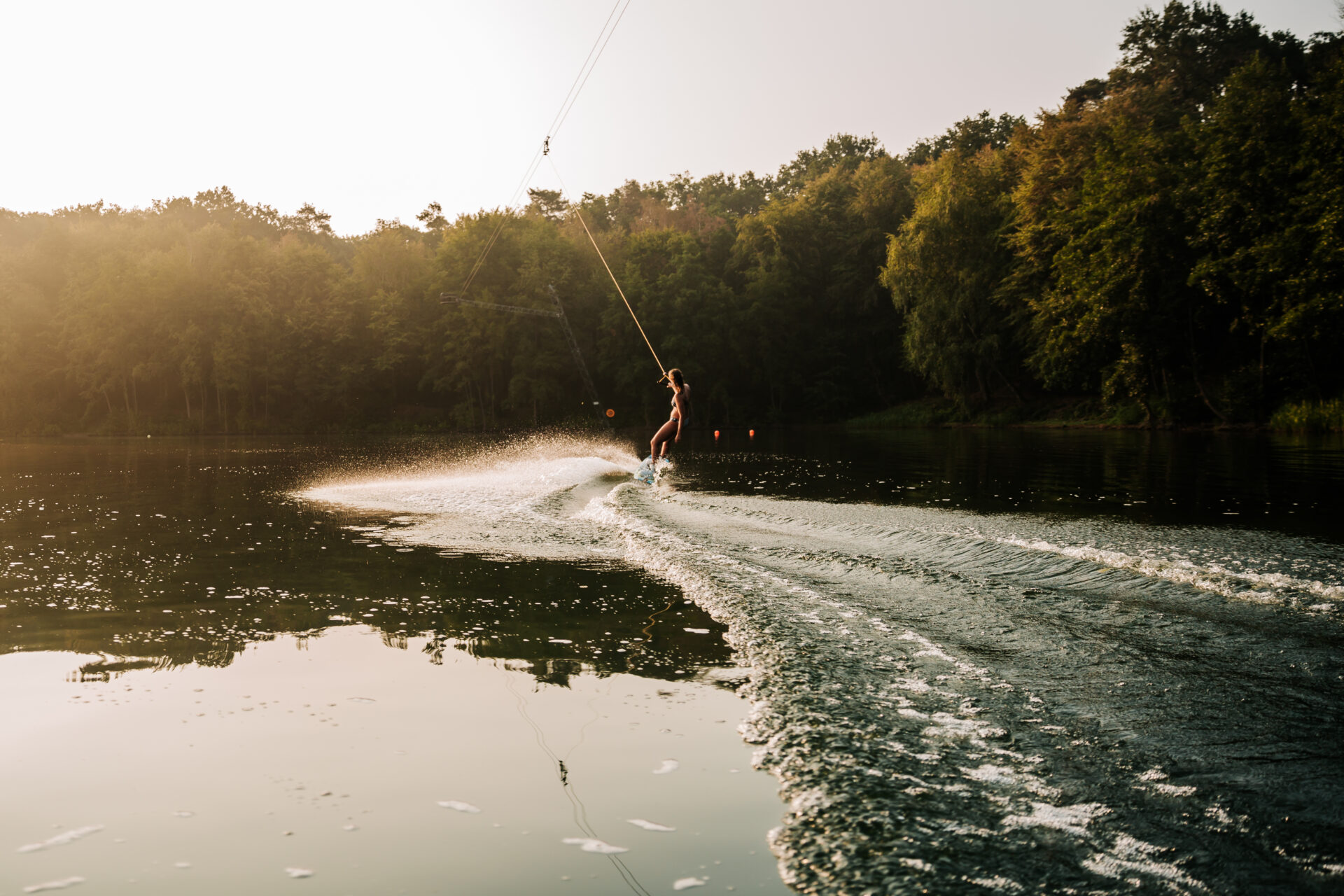 Mädchen im Bikini auf einem Wakeboard in der Morgensonne