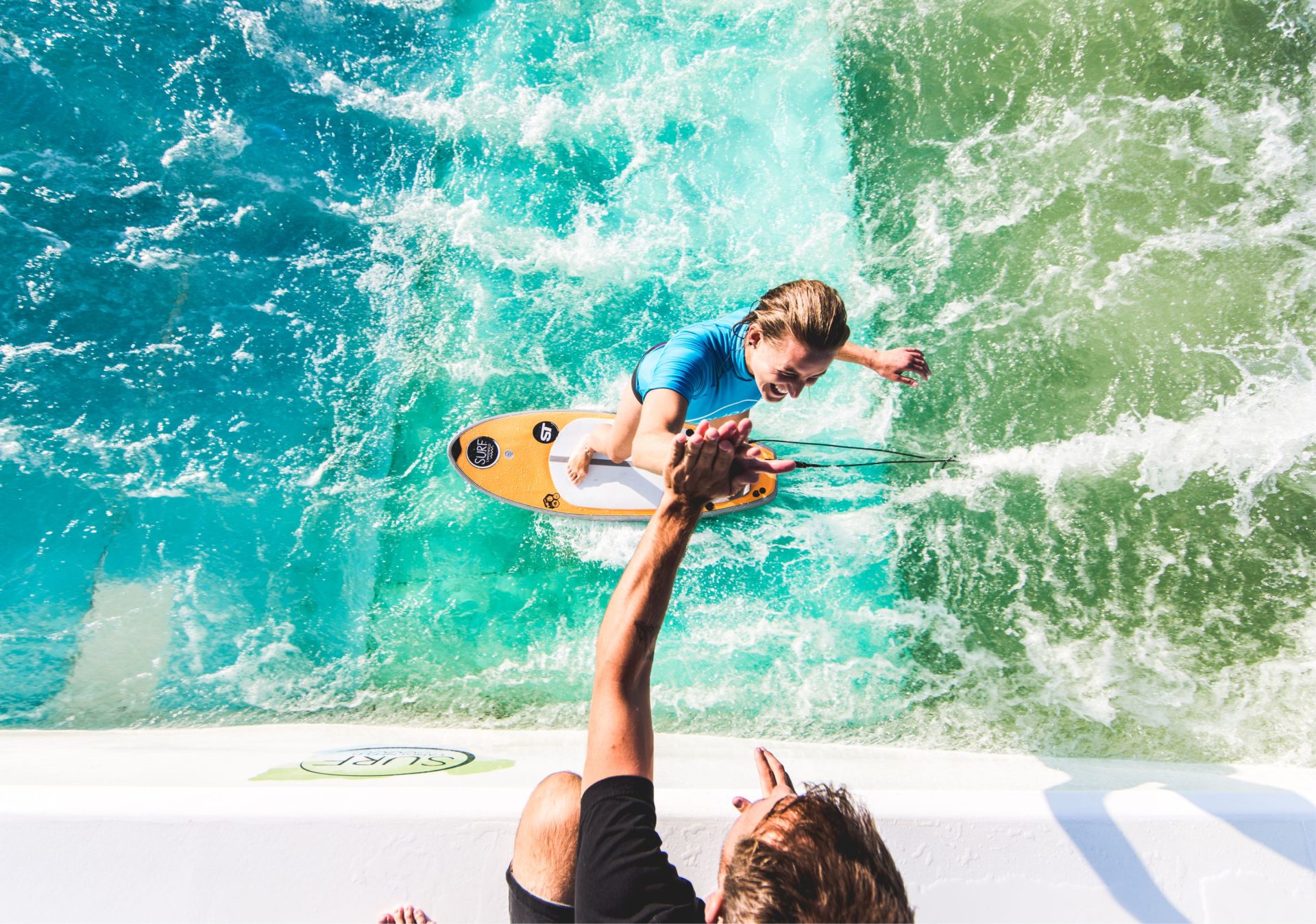 surf-langenfeld-job-surf-pool-manager Surf Coach gibt einem Surf-Anfängerauf der Welle eine High Five