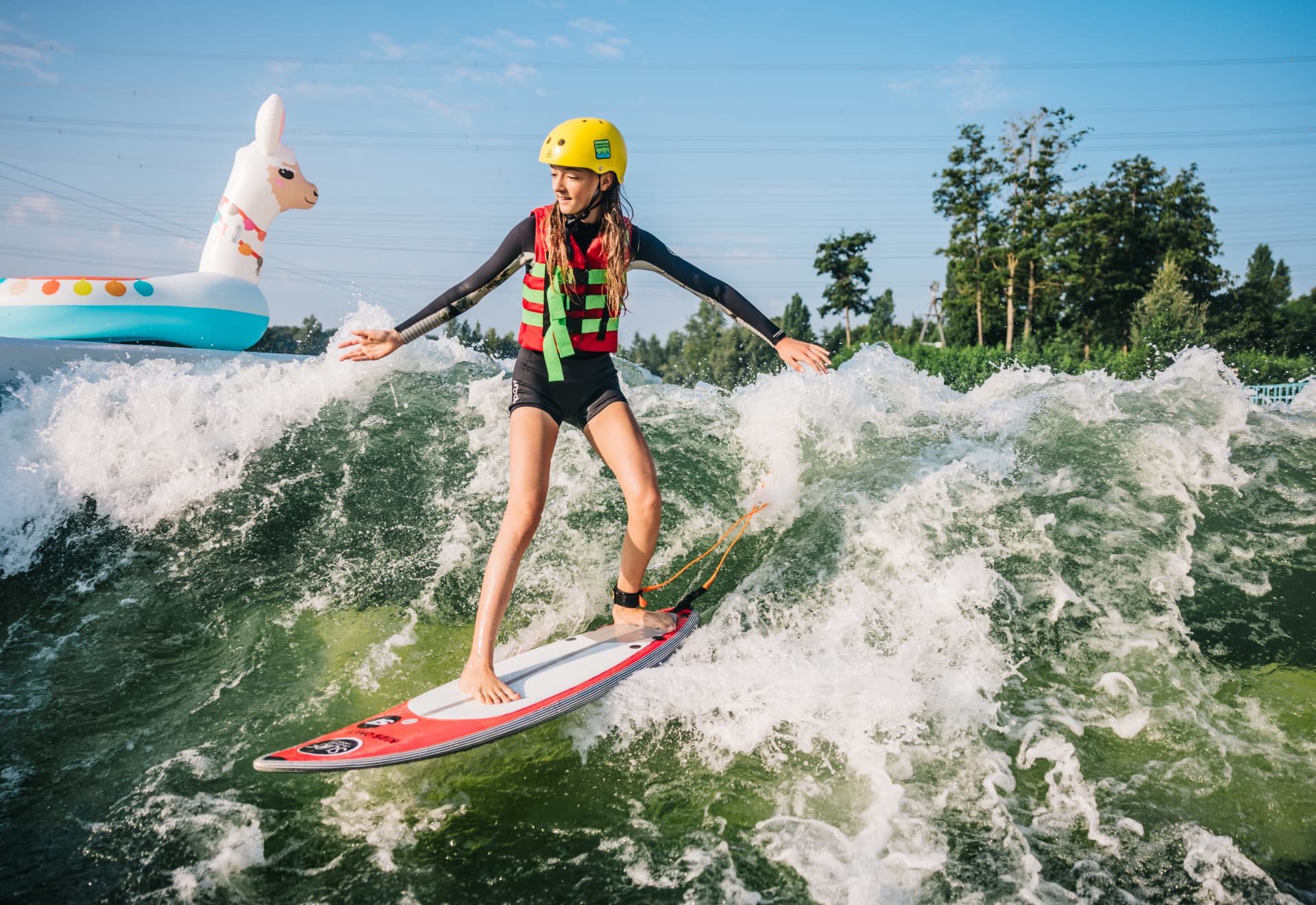 Kind surft auf stehender Welle mit Helm und Schwimmweste